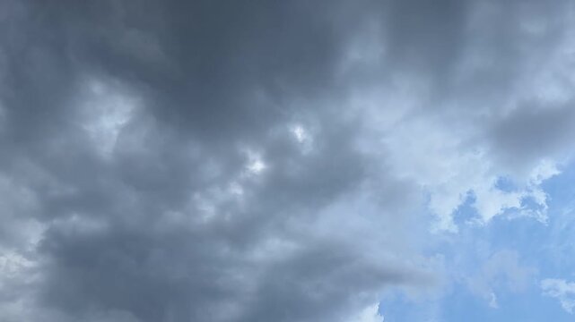 Wide sky view of dark storm clouds gathering, leaving a small patch of blue visible on the right.