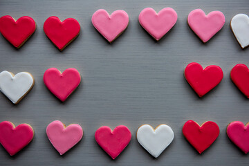 Fototapeta premium Heart-shaped cookies in red, pink, and white on a gray surface.