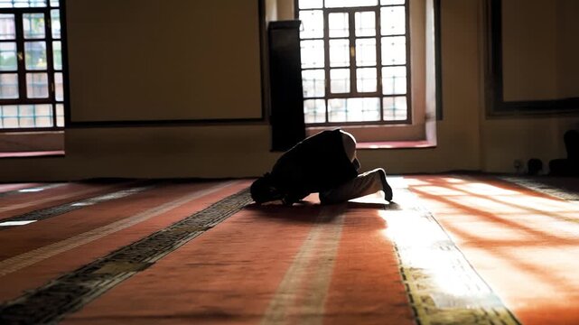 Bursa Ulu Cami interior with a man praying and worshipping inside the historic Ottoman mosque. Cinematic indoor view of a Muslim believer.