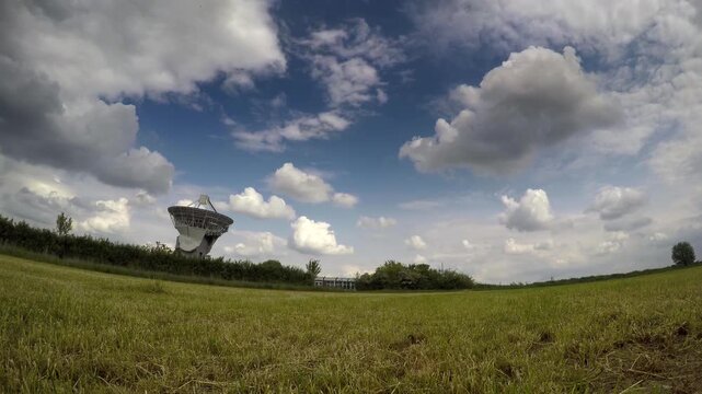 landscape with time-lapse clouds above a radio dish, uk