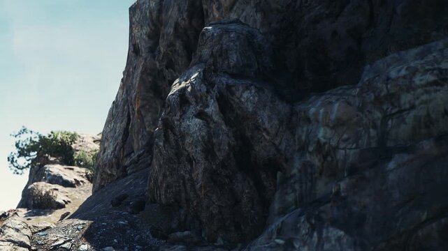 A large rock formation stands tall on a mountain. Small trees grow near the top. The sun shines brightly, casting shadows on the rocky surface. The scene shows nature in a clear sky.