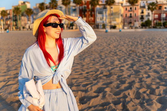 Young redhead woman looking out on villajoyosa beach at sunrise