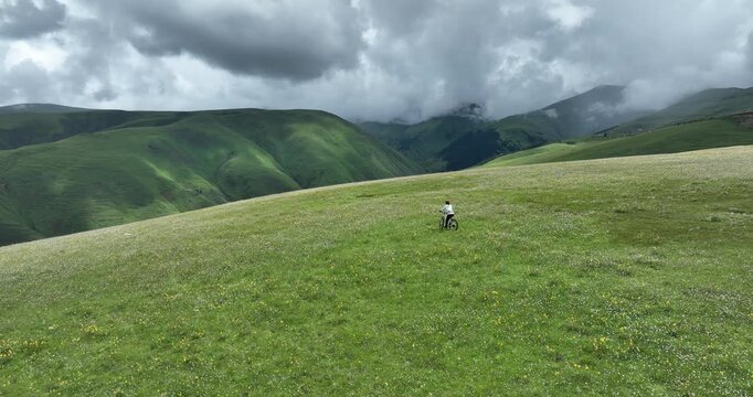 Aerial footage of woman riding mountain bike on beautiful grassland mountain trail, slow motion