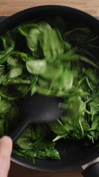 Stirring Fresh Spinach In Pan Top View Vertical