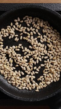 Stirring Pine Nuts In Pan Top View Vertical