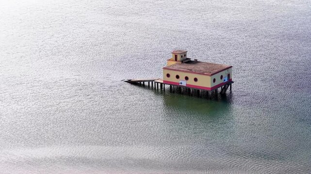 Aerial view of the historic lifeguard station on stilts surrounded by the calm waters of the Ria Formosa lagoon near a sandbar in Fuseta, Faro District, Portugal.