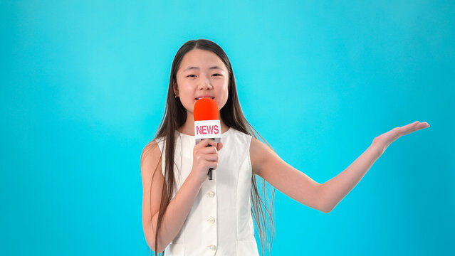 Girl holding microphone pointing to side on blue background