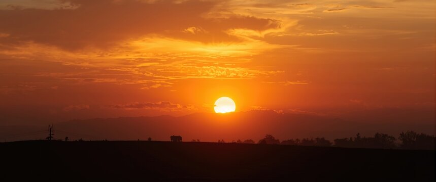 Sunset over rolling hills with vibrant orange sky