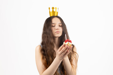 Woman with a small crown eating a cake isolated on blue
