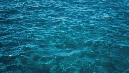 Obraz premium Blue ocean water with ripples and sunlight reflections