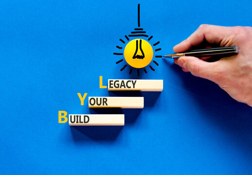 BYL build your legacy symbol. Concept words BYL build your legacy on beautiful wooden blocks. Beautiful blue background. Businessman hand. Business BYL build your legacy concept. Copy space