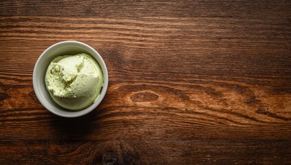 Obraz premium Pistachio ice cream in a white bowl on wooden table