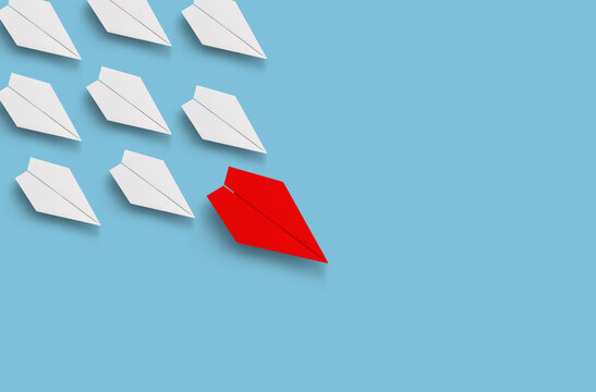 Red paper airplane leading formation of white paper airplanes across blue background with strong
