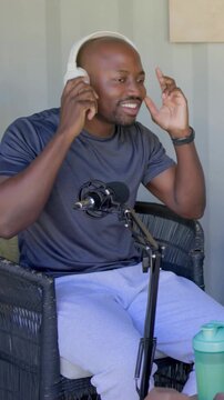 Vertical video: Reaching for white headset, host in dark tee starting podcast in studio, on mic