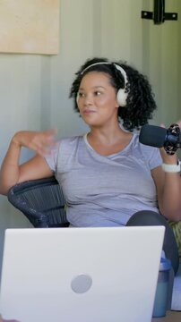Vertical video: Recording woman headset speaking gesturing at mic at home laptop for podcast
