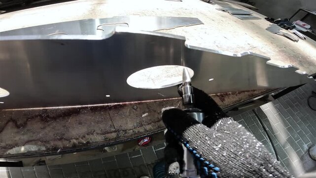 Worker operates a grinder. Grinding and processing of an aluminum part, first-person view. Shipyard, processing an aluminum part. Production of an aluminum hull for a motorboat.