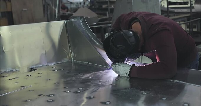 Production of an aluminum hull for a motorboat. Welding process. Close-up of welding an aluminum boat hull or aluminum alloys.  Boat production. Production site. Welding process in the shop. Shipyard