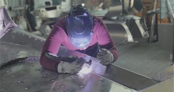 Production of an aluminum hull for a motorboat. Welding process. Close-up of welding an aluminum boat hull or aluminum alloys.  Boat production. Production site. Welding shop.
