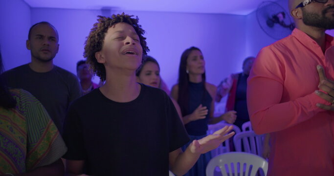 Young boy sings with joy during uplifting church worship service, surrounded by congregation celebrating in spiritual unity and praise