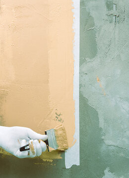 Hand paints wall with soft, warm tone