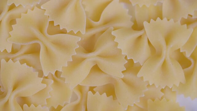 Unprocessed pale yellow farfalle with zigzag cuts and ruffled edges. Detailed closeup of uncooked pale yellow bowtie pasta with textured ruffled edges and zigzag cuts