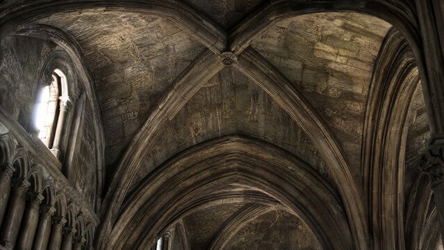 Intersecting stone arches of a Gothic cathedral ceiling meeting at a precise groin vault.