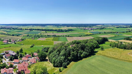 Naklejka premium Historischer Römerturm inmitten eines dichten, grünen Waldstücks, umgeben von weiten Feldern und Wiesen in einer idyllischen ländlichen Landschaft aus der Vogelperspektive fotografiert.