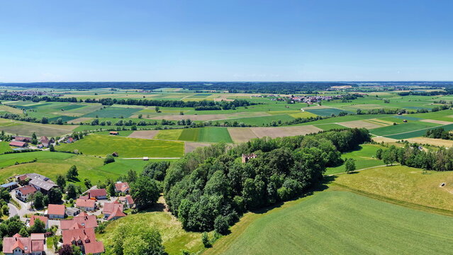 Historischer R&ouml;merturm inmitten eines dichten, gr&uuml;nen Waldst&uuml;cks, umgeben von weiten Feldern und Wiesen in einer idyllischen l&auml;ndlichen Landschaft aus der Vogelperspektive fotografiert.