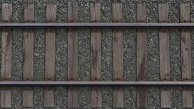 Top-down view of parallel railway tracks and wooden sleepers creating geometric lines.