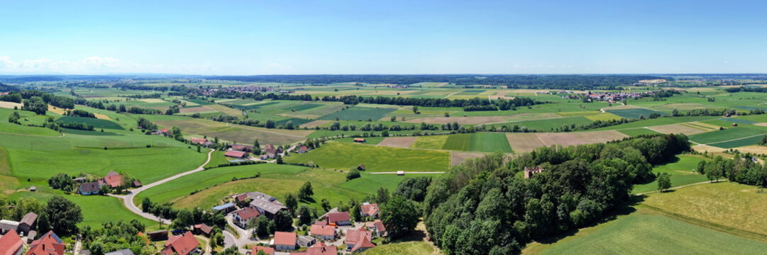 Historischer R&ouml;merturm inmitten eines dichten, gr&uuml;nen Waldst&uuml;cks, umgeben von weiten Feldern und Wiesen in einer idyllischen l&auml;ndlichen Landschaft aus der Vogelperspektive fotografiert.