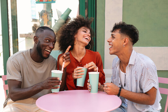 Three happy friends toasting refreshing summer drinks at a vibrant outdoor cafe, celebrating the joy