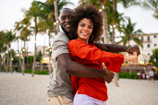 Young happy couple on a romantic honeymoon trip, embracing at tropical beach during summer vacation