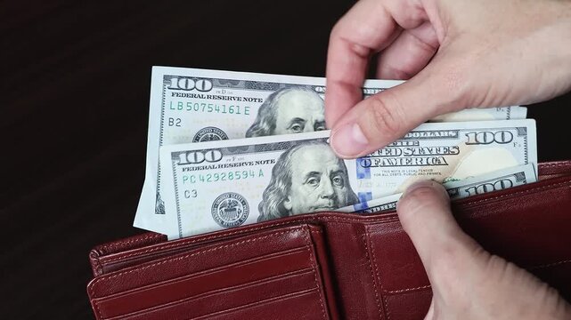 Female hands counting 100 US dollar banknotes (USD) in a leather wallet. American cash money, concept of money circulation, financial security. Real time footage.