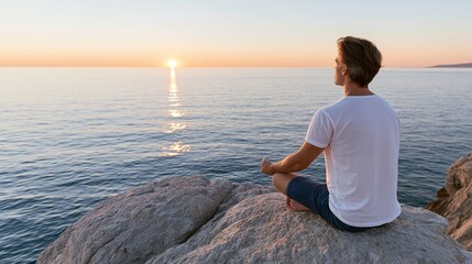Fototapeta premium Man meditating on a rock by the sea at sunrise, finding inner peace