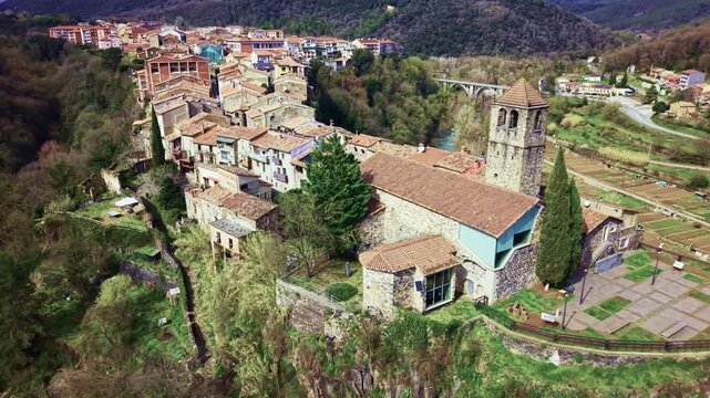 Drone orbit around church and volcanic cliff of Castellfollit de la Roca.