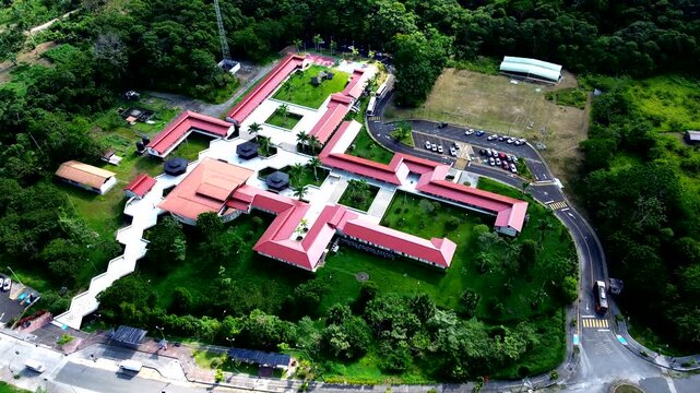 Drone View of Large Red Roof Resort in Ecuador Rainforest, Road, Parking Area, Green Tropical Forest and Mountain Tourism Infrastructure Scene
