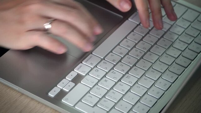Close-up video of female hands typing on a white laptop keyboard, showing focused work, modern technology, productivity and digital lifestyle concept.