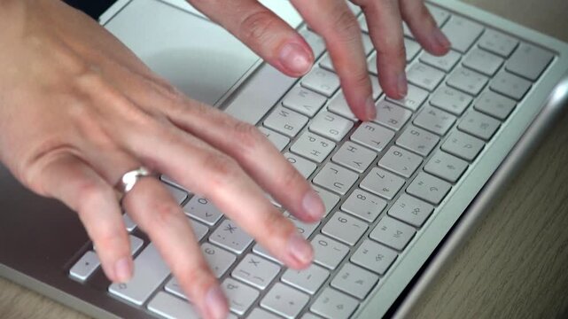 Close-up video of female hands typing on a white laptop keyboard, showing focused work, modern technology, productivity and digital lifestyle concept.