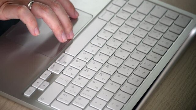 Close-up video of female hands using the touchpad of a white laptop, showing focused work, modern technology, navigation, productivity and digital lifestyle concept.