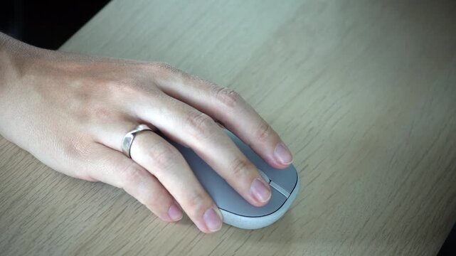 Close-up video of a female hand using a wireless mouse on a desk, showing focused work, modern technology, navigation, productivity and digital lifestyle concept.
