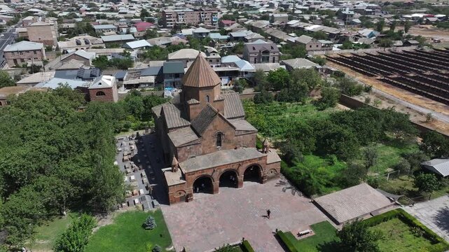 An aerial drone shot captures the historic Saint Gayane Church, an ancient Armenian apostolic church showcasing its beautiful stone architecture and green courtyard in the city of Vagharshapat.

