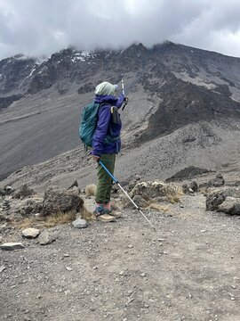 Active Senior Asian Woman Hiker Pointing to Kibo Peak on Mount Kilimanjaro Tanzania