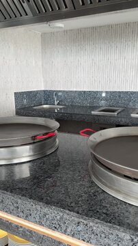Large electric frying pans in a restaurant kitchen, commercial cooking equipment, chefs preparing meals, professional grade.