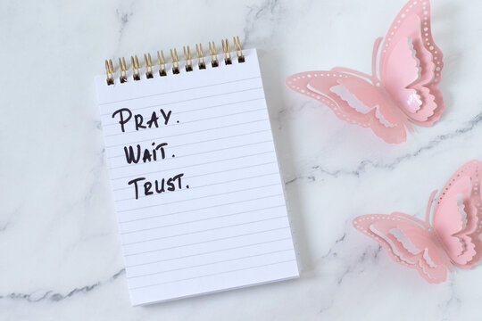Pray, wait, trust, christian encouragement text in a notebook. Biblical concept of patience and faith in God Jesus Christ.