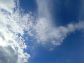 Fototapeta premium Scattered white clouds in a vibrant blue sky. Daytime weather and atmosphere background