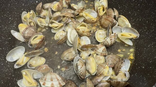Vongole clams in a hot skillet, garlic butter sauce, sizzling seafood, Italian dish, aromatic.