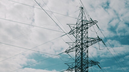 High Voltage Power Lines Standing Tall Against a Dramatic Cloudy Sky Forming a Striking Scene © beholdereye