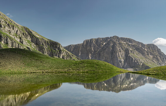 Rugged Pindus mountain cliffs above Dragon Lake reflection, mount Tymfi, Greece