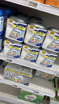 Oshawa, Canada - august 19 2023. Similac formula cans sit on a store shelf. Prices and labels are visible. Shoppers can see different products in the scene.