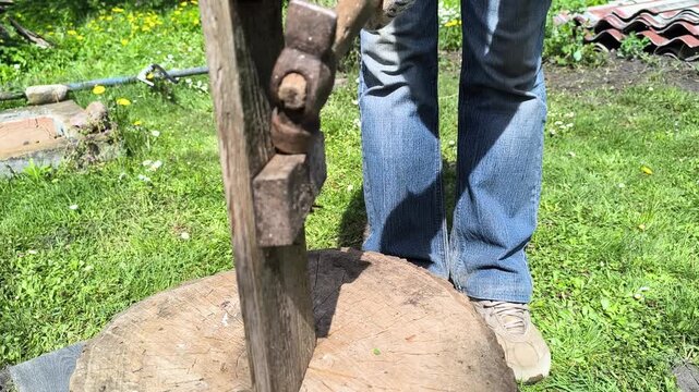 a young man tries to break a piece of wood with a hammer